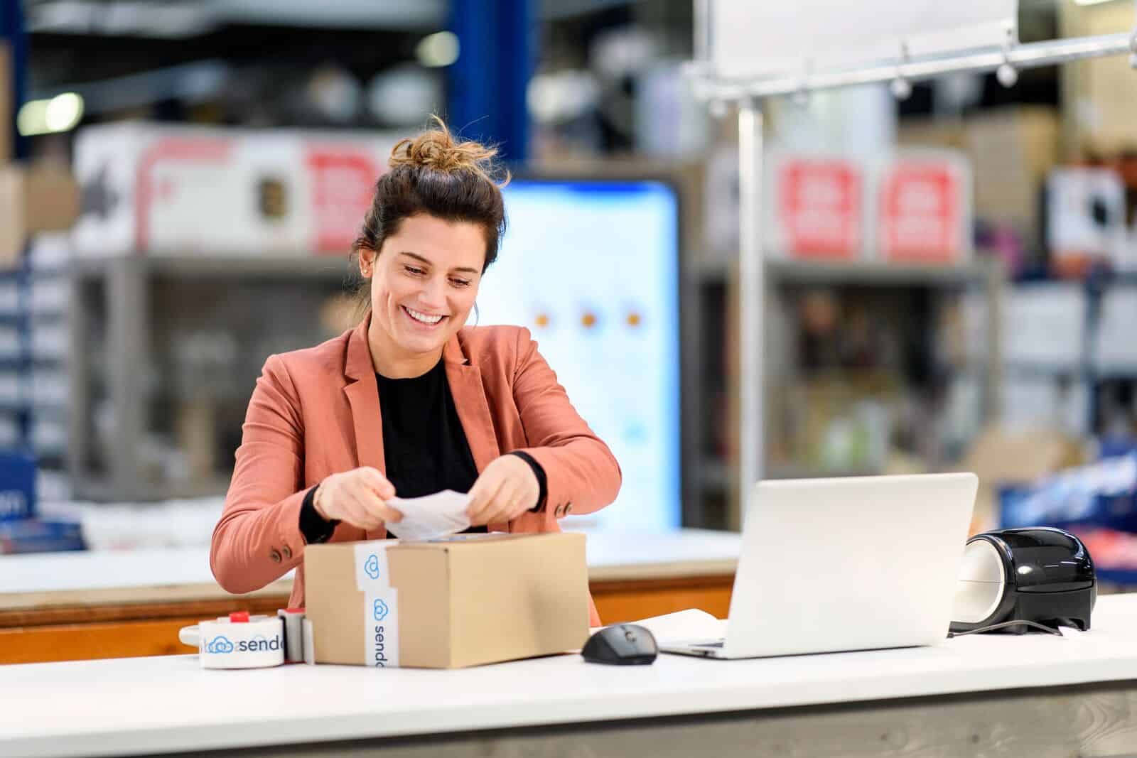 Female worker packing expedited shipping Sendcloud package.